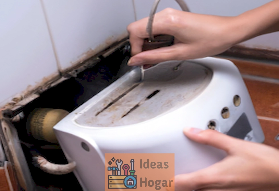 Manos descalcificando un calentador de agua sin tanque con herramientas y productos de limpieza.