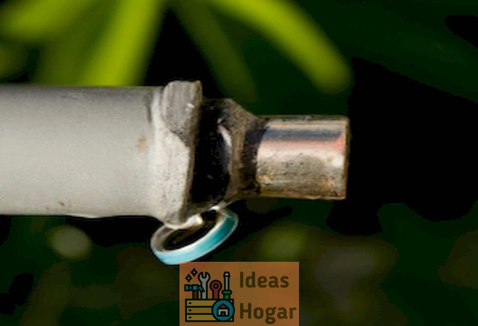 Imagen de una llave de paso cerrada con una fuga de agua en una tubería exterior en el jardín.