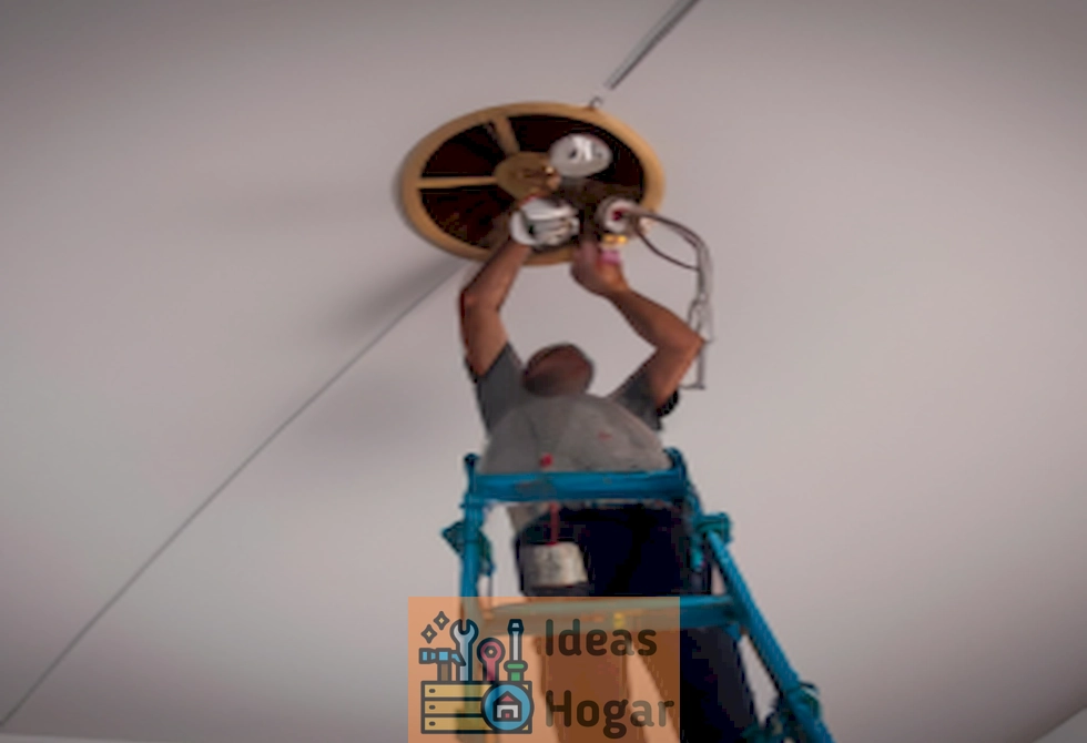 Imagen de un electricista instalando un candelabro en un techo alto en 2024
